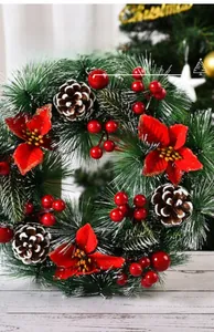 Close-up of artificial Christmas wreath with red poinsettias, pine cones and snow details