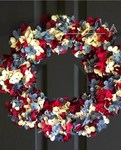Detailed close-up of a festive floral wreath with red and blue hydrangea blossoms on wood