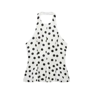 Detail eines weißen Neckholder-Tops mit schwarzen Punkten und Rüschen am Saum
