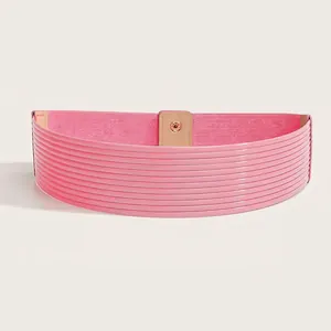 Detail van de brede roze elastische riem met glanzend lakleer en gouden knoopsluiting
