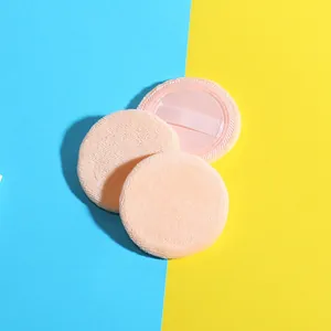 Three round pink cosmetic powder puffs with ribbon handles on blue and yellow background