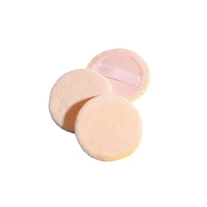 Three round pink cotton powder puffs with ribbon handles on a minimalist white background