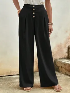 Detail of high waisted wide leg black cotton pants with decorative brown buttons