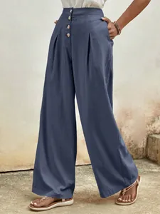 Detailed close-up of dark grey-blue wide-leg cotton pants with waist pleats and buttons