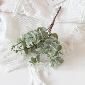Detailed view of frosted faux eucalyptus leaves on a white woven textured blanket