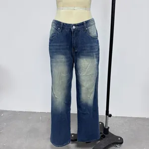 Detail of dark blue denim jeans with metal button and whiskered wash on the waistband