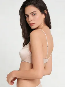 Détail du tissu satiné et de la dentelle sur un soutien-gorge rose nude avec bretelles