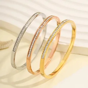 Close-up of gold, silver, and rose gold titanium bangles with sparkling micro-pave crystals