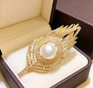 Detailed macro of a gold feather brooch with a white pearl and sparkling crystals in a box