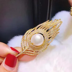 Elegant gold feather brooch with shimmering crystals and a central white pearl