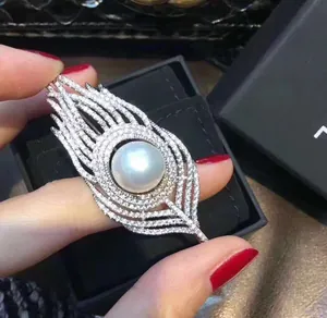 Detailed view of feather brooch featuring large white pearl and pave-set rhinestones