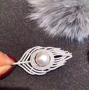 Exquisite silver feather brooch featuring a large center pearl and sparkling crystals