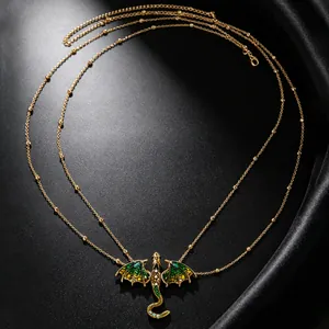 Detail of a gold dragon necklace with green enamel wings and zircons on black silk