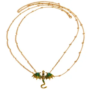 Detail of vintage golden dragon necklace with green enamel wings on white background