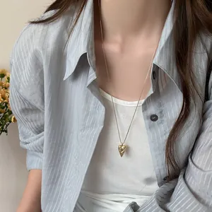 Detail view of a gold-plated pointed heart necklace with engraved stars on a model