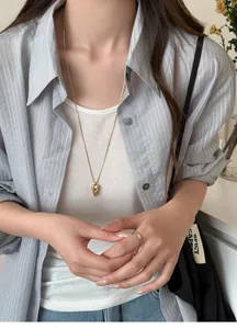 Detail view of a stylish gold heart pendant necklace on a model's outfit