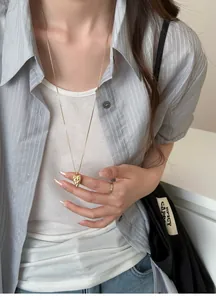 Detailed view of a unique gold pointed heart totem necklace on a model in Korean style