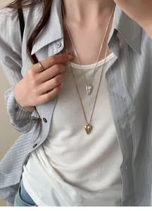Detail shot of stylish layered pointed heart totem necklaces in gold and silver finishes