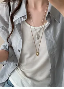 Close-up detail of layered gold and silver pointed heart necklaces with unique totem patterns