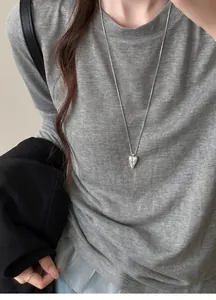 Silver necklace with heart-shaped pendant featuring unique abstract face engraving