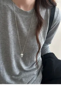 Detailed close-up of a silver-toned pointed heart pendant necklace with vintage engraving