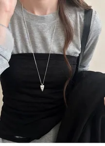 Unique silver heart totem necklace worn by a model, showing niche design details