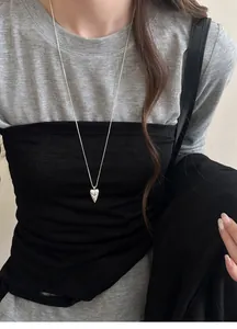 Chic silver pointed heart pendant necklace with tribal totem design worn for styling.