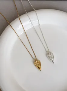 Close-up of gold and silver heart pendant necklaces featuring unique engraved tribal patterns