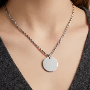 Détail macro d'un pendentif rond en argent poli sur une chaîne en corde d'acier