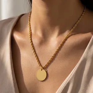 Gros plan d'un collier en acier titane plaqué or 18 carats avec un pendentif rond minimaliste.