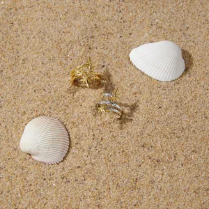 Detailopname van achtpuntige sterringen met zirkonen op een zandstrandachtergrond