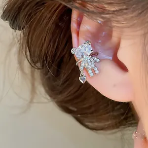 Macro detail of a silver bear-shaped ear cuff featuring clear crystals and heart charm