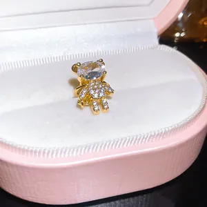 Detailed view of a gold teddy bear ear cuff with sparkling stones in a pink jewelry box.