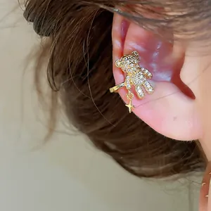 Close-up view of crystal-encrusted gold bear ear cuff with a dangling star detail