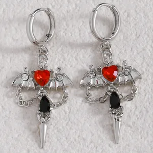Detail of gothic silver earrings with bat wings, red heart, and black teardrop gem