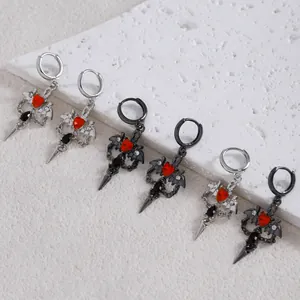 Detail of gothic earrings with bat wings, red heart gemstones, and dagger elements