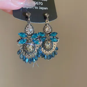 Close-up of silver needle crystal tassel earrings with turquoise and clear stones.