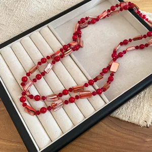 Detail of elegant red glass bead and faux shell necklace displayed in a jewelry tray.