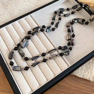 Detailed shot of faux shell and glass bead necklace with a vibrant iridescent finish