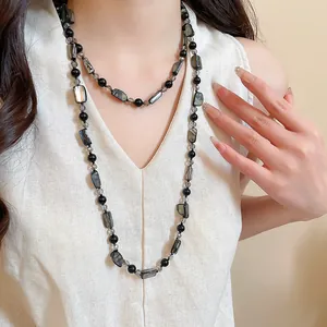 Detailed view of layered bohemian necklace with faux shell and black glass beads