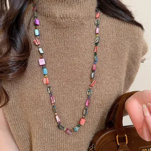 Detail view of a long necklace with colorful faux-shell beads and glass accents.