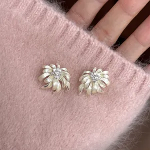 Close-up of elegant firework-shaped stud earrings on a pink knitted sweater sleeve.