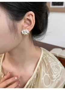 Close-up detail of a cream floral firework stud earring with rhinestone worn by a model