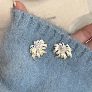 Detail view of flower stud earrings with rhinestones on a blue fuzzy sweater