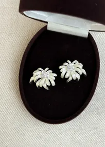 Close-up of elegant firework-shaped stud earrings with crystals and cream enamel finish