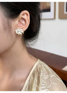 Close-up of French style firework stud earrings with enamel petals and rhinestone center.