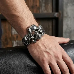 Punk skeleton cuff bracelet featuring three skull motifs on wide black leather strap