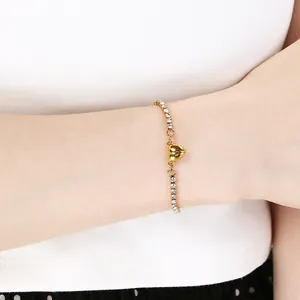 Dettaglio ravvicinato di un elegante bracciale tennis dorato con chiusura magnetica a cuore al polso