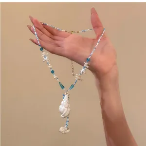 Detailed view of a blue beaded summer necklace with starfish and shell charms in hand.