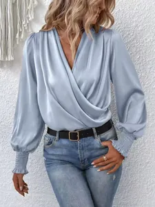 Detail of light blue smocked cuffs on a V-neck satin blouse with elegant draped sleeves
